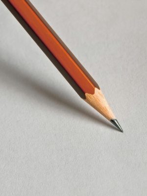 Detailed close-up of a wooden pencil resting on white paper, perfect for educational themes.