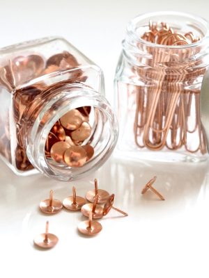 Close-up of copper stationery items in elegant glass jars, perfect for office decor.